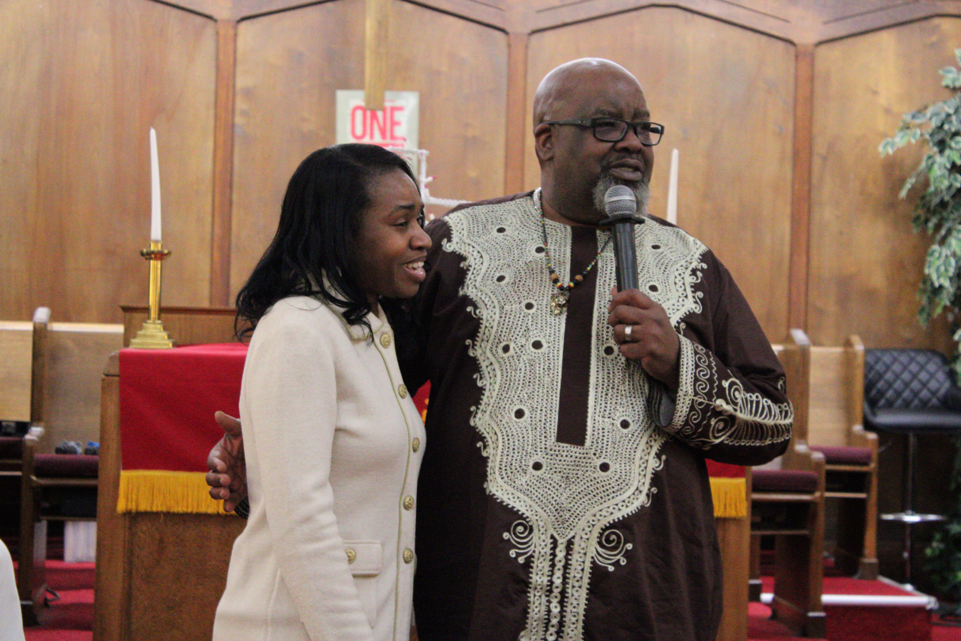 Pastor and first lady sharing a warm moment while addressing the congregation