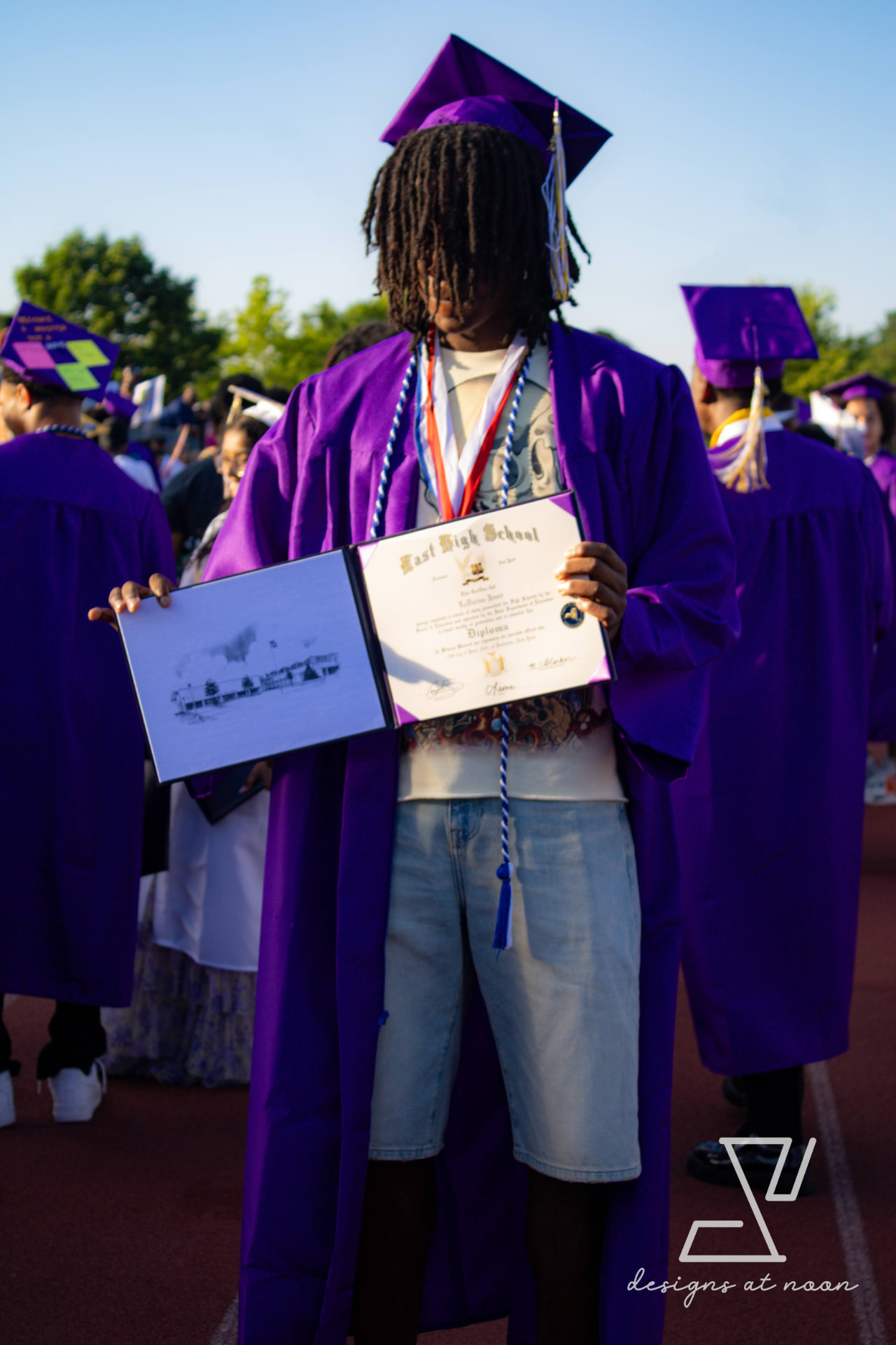 Graduate holding an East High School diploma in a purple gown