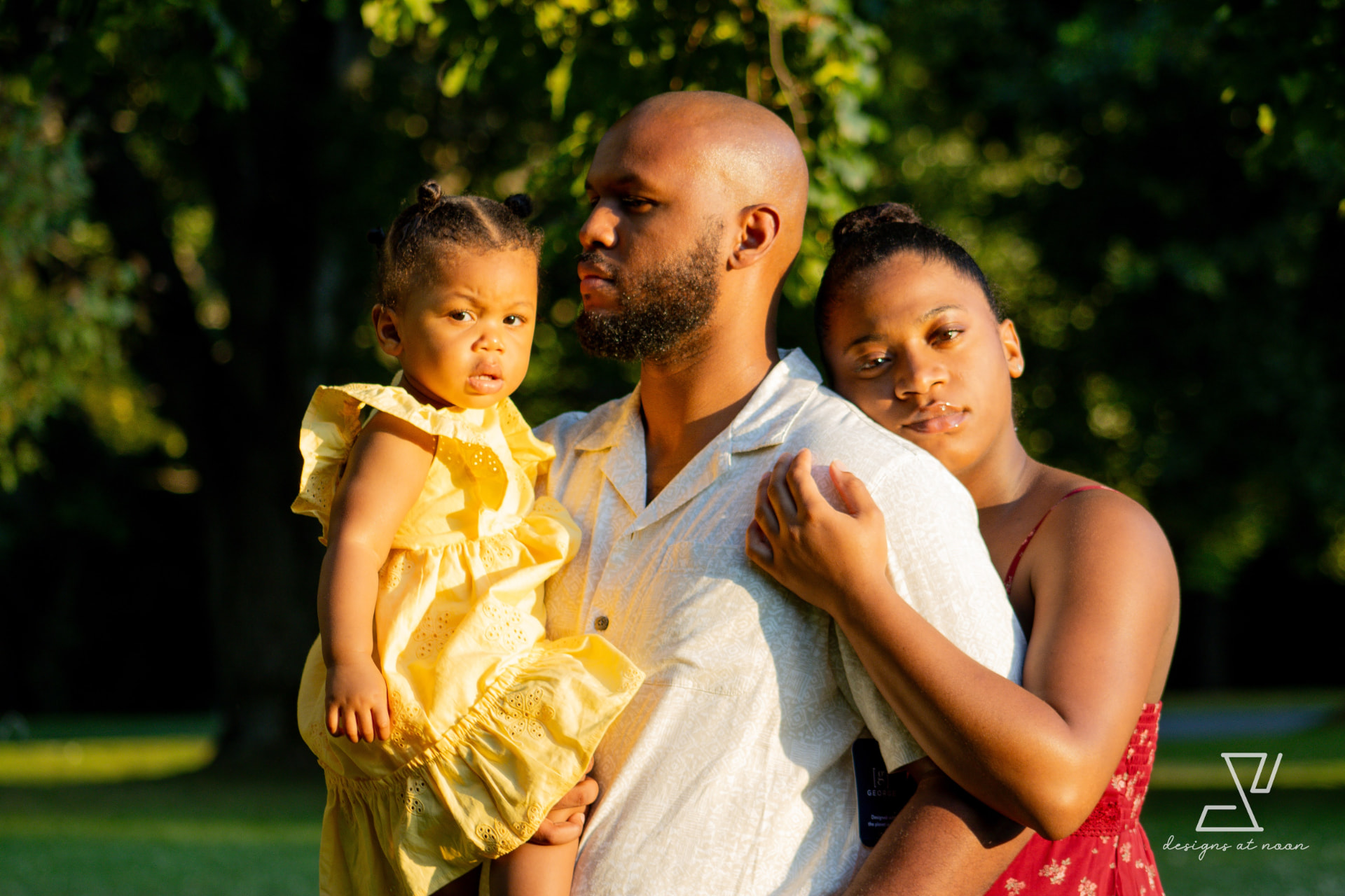 Family of three holding each other in golden evening light, upstate New York park