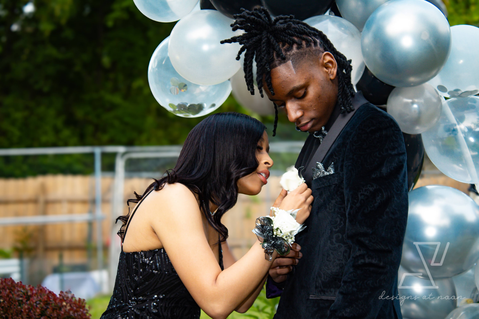 Prom couple pinning a boutonniere beneath a balloon arch, upstate New York