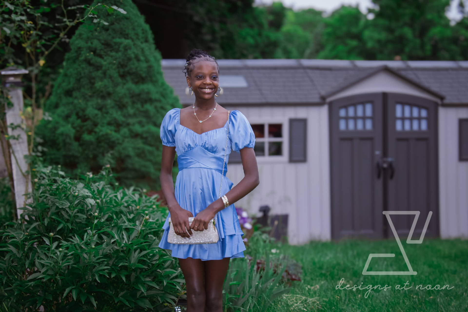 Young girl in a light blue dress smiling in a backyard garden, upstate New York