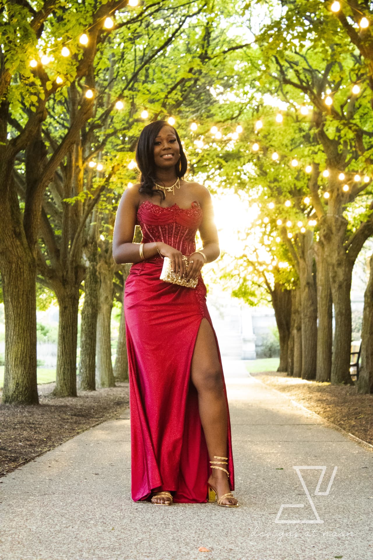 Prom portrait in a red glitter gown beneath a canopy of string lights