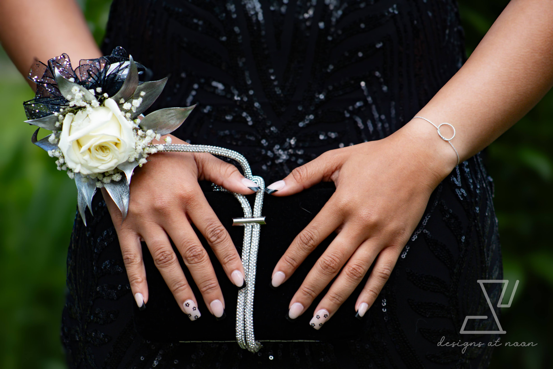 Detail of a white rose corsage and clutch against a black sequin gown
