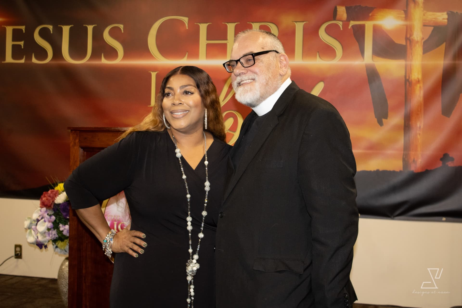 First lady and pastor posing together in front of the sanctuary banner