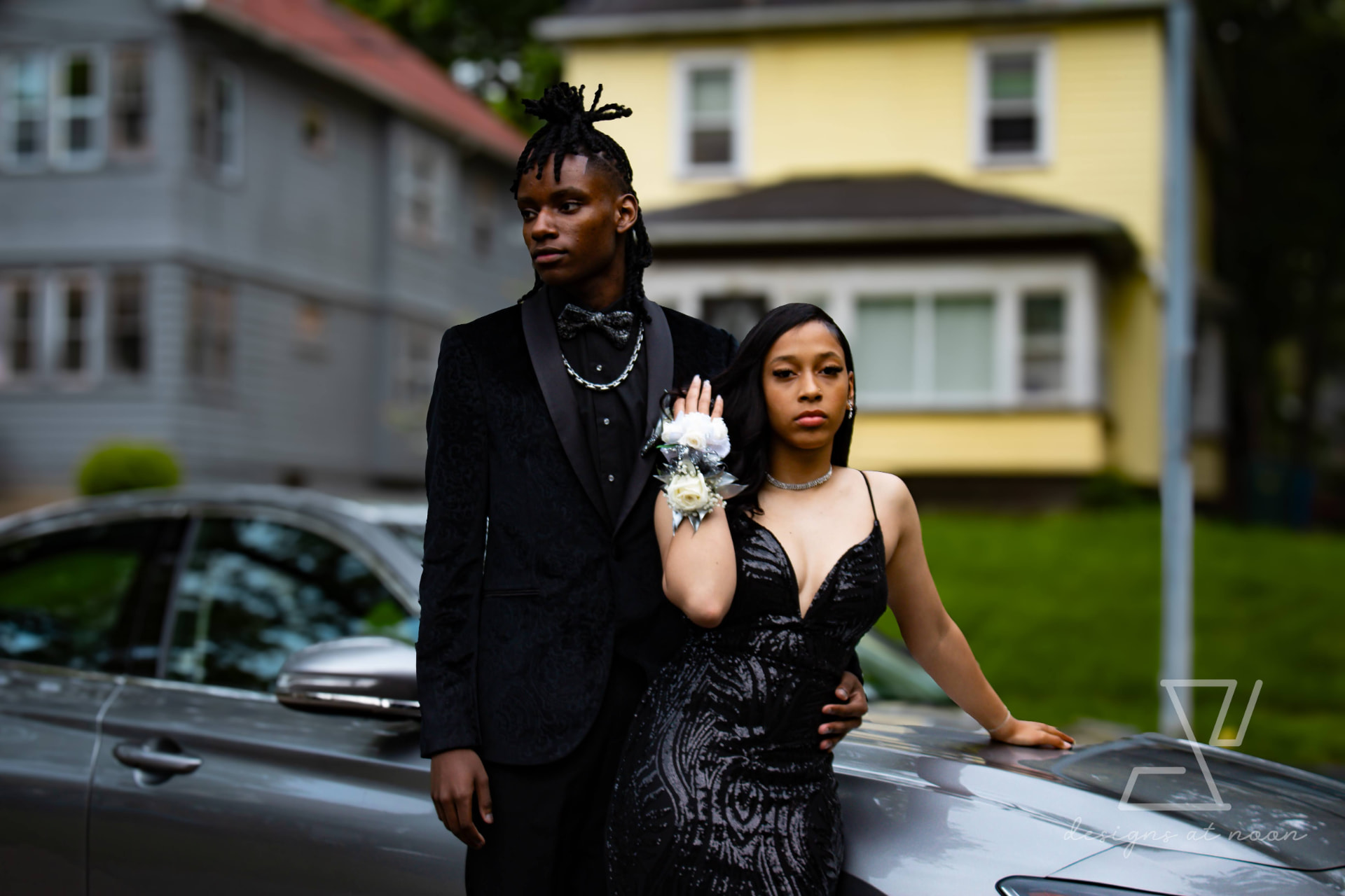 Prom couple posing beside a car on a tree-lined upstate New York street