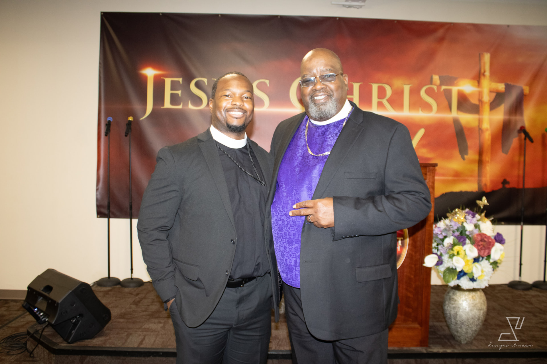 Two ministers standing together in front of the sanctuary banner