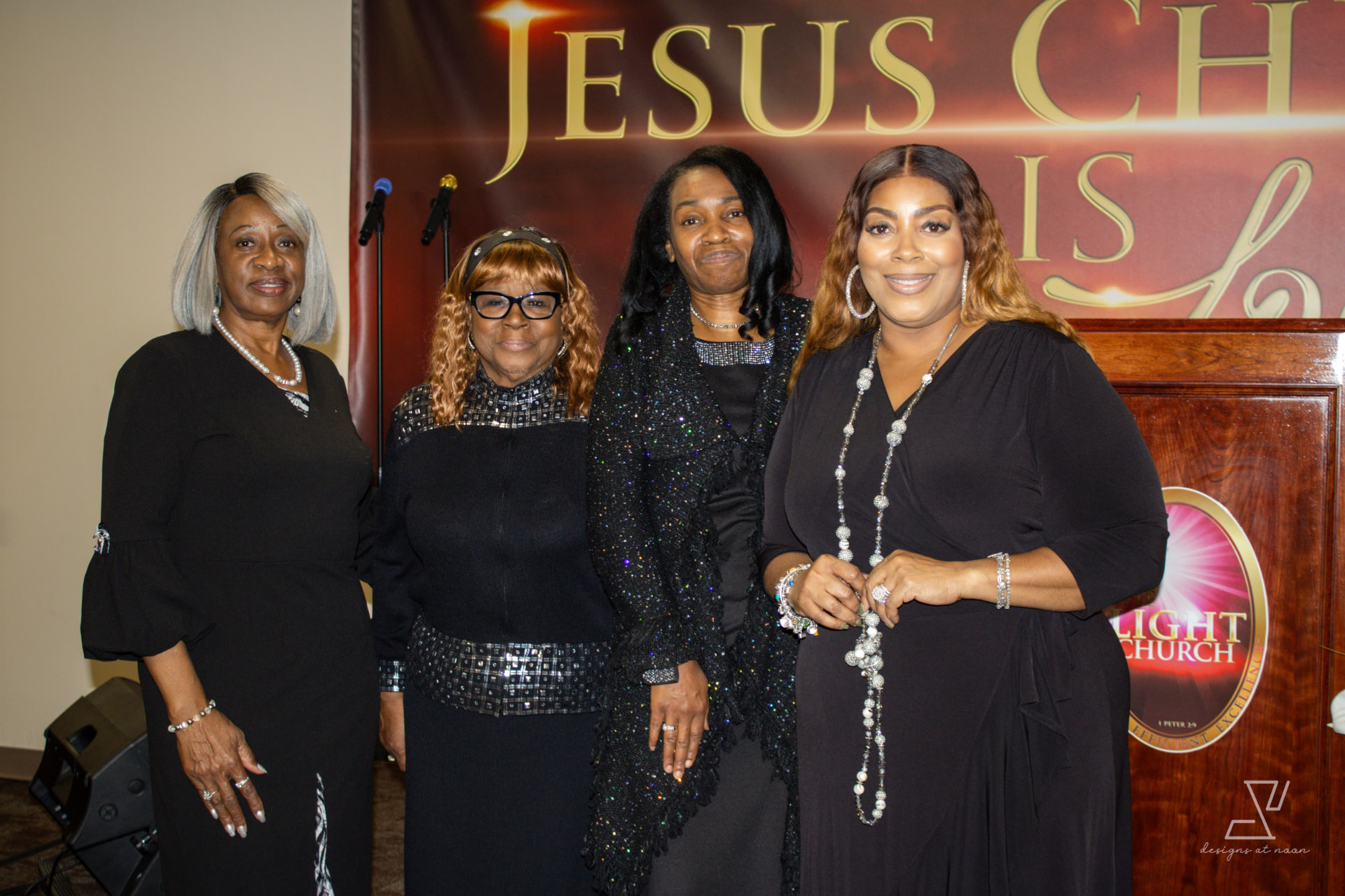 Four church mothers posing together beside the pulpit